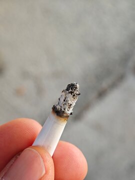 Close-up of Hand Holding a Lit Cigarette with Ash