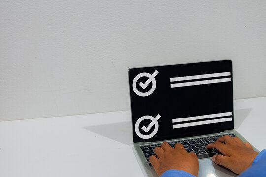 A businessman typing on a laptop displaying a digital checklist overlay on a white desk. Concept of task management, online survey, goal achievement, and completing a to-do list.