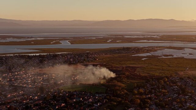 AMERICAN CANYON, CA - JULY 25, 2026: Wide aerial view of a smoke column from the Dutch Flat Fire rising at the edge of town above tidal wetlands and San Pablo Bay in hazy light.