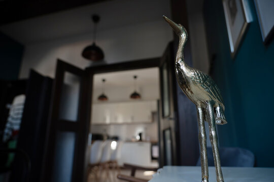 Metal bird figurine in home interior with blurred background