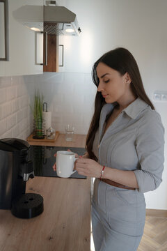 Woman holding fresh coffee in modern home kitchen