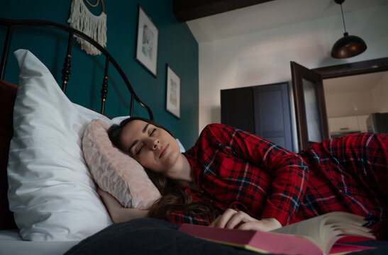Woman falls asleep while reading a book in bed