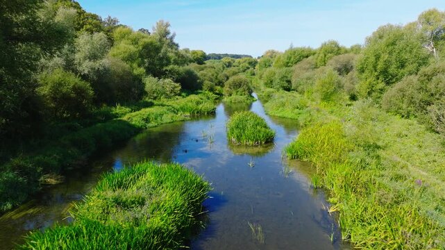 Drone shot flying along and downstream the River Avon in the Woodford Valley on a summer day. Wiltshire UK