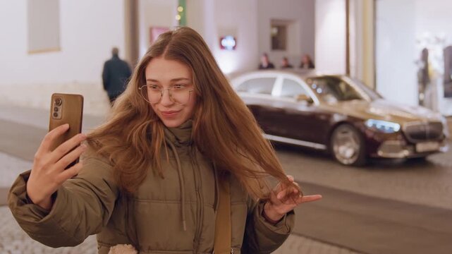 Luxury hotel entrance with smiling influencer. Vibrant social media scene at upscale hotel. Dynamic influencer recording cheerful selfie at highend hotel entrance with car and boutique window