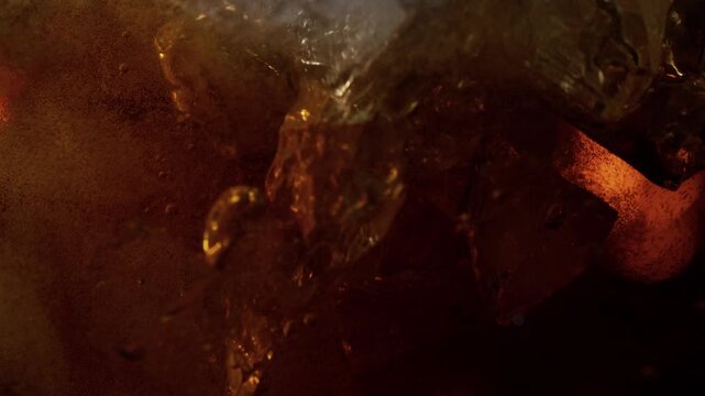 Super Slow Motion Shot of Ice Falling into Fresh Cola Lemonade at 1000fps.
