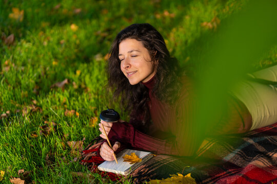 Person writes notes lying on the lawn in the autumn park. Solitude with yourself