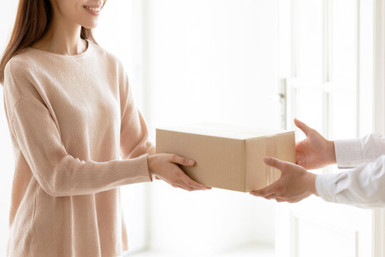 玄関で宅配便の段ボール箱を笑顔で受け取る女性
