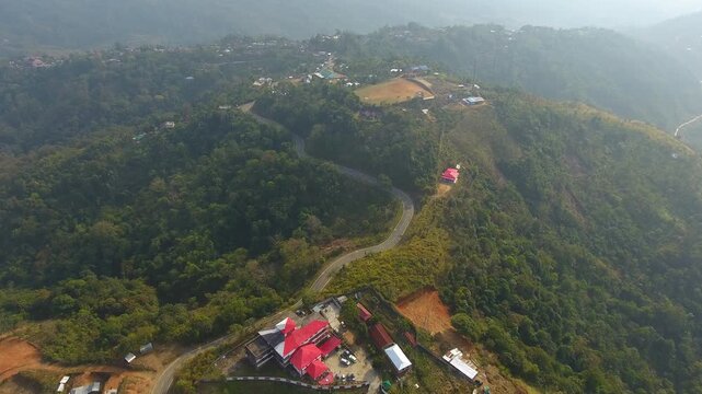 Aerial top view drone shot of a winding road passing through lush green hills in Haflong, Dima Hasao, Assam, India. Stock footage