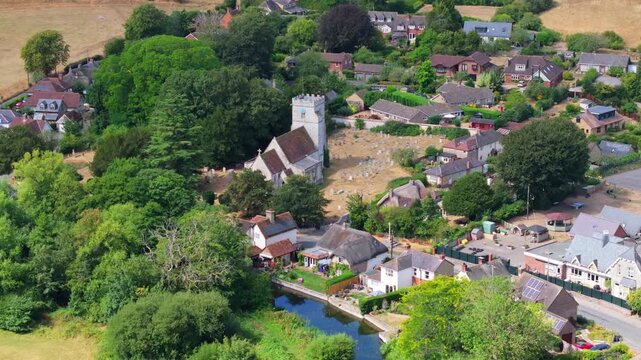 Tracking aerial shot of All Saints parish church and surroundings in Middle Woodford, Wiltshire, UK