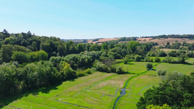 Aerial shot flying over the Woodford Valley south from Lower Woodford Village in summer, Wiltshire, UK