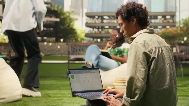 The student reviews renewable energy data on a laptop during campus study, with clean energy information and a blurred outdoor academic background.