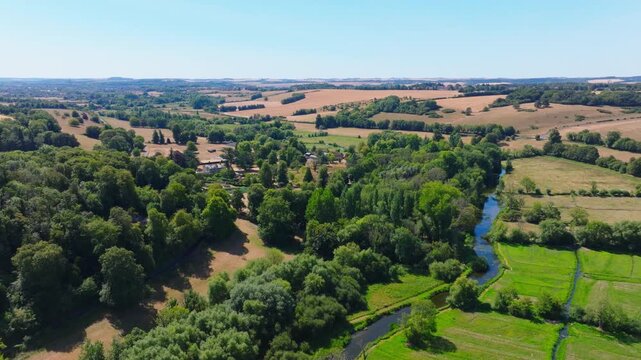 Aerial shot flying over the Woodford Valley south from Lower Woodford Village in summer, Wiltshire, UK