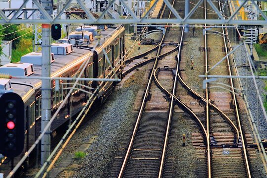 夕日の光に輝く線路とポイント分岐を通過する電車