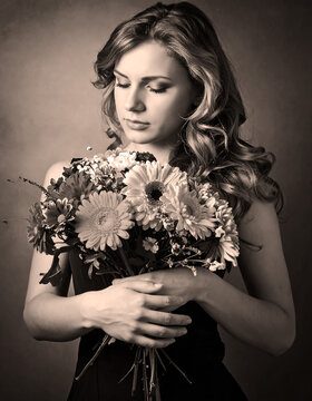 Woman deep in thought caressing a bouquet of flowers.