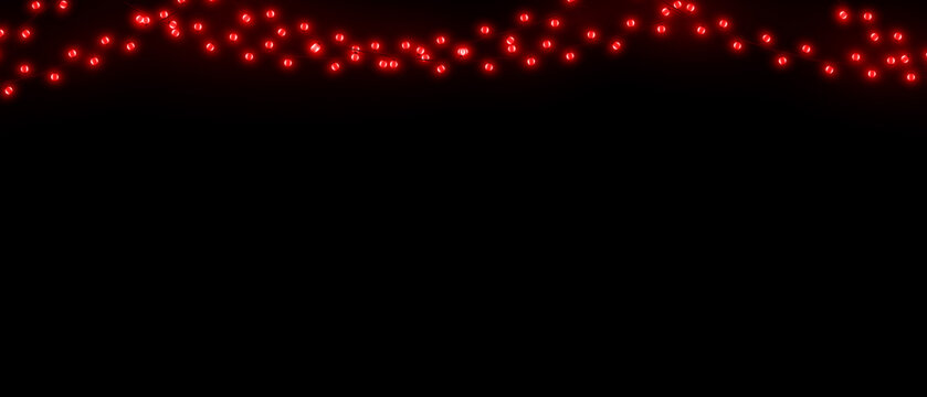 A festive string of glowing red christmas light bulbs hanging against a dark black background for holiday decoration