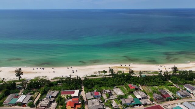 Aerial view of peaceful coastal fishing village with turquoise sea and white sand beach in Quang Tri Vietnam