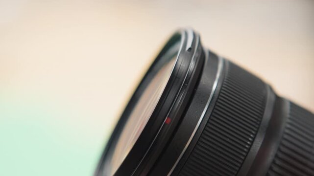 Macro lens barrel closeup studio, polished metal mount, focus ring texture, glass elements catching soft green reflection, shallow depth of field, product photography, minimal background, clean