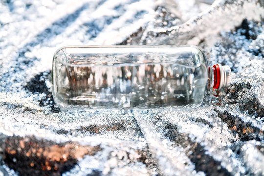 Clear glass bottle with water on sparkling sequins background