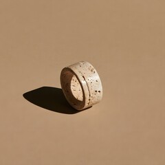 Fototapeta premium Sculpted travertine stone ring on beige backdrop