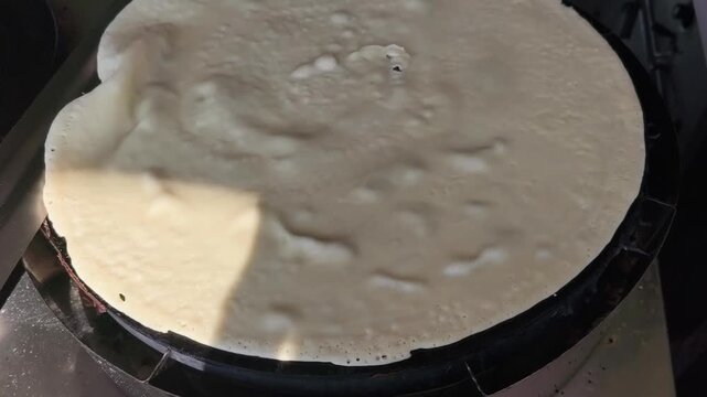 Crepe cooking on a hot griddle in sunlight