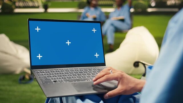 The student holds a laptop with a blue screen mockup and uses the touchpad with one hand, an isolated chroma key screen ready for replacement on the computer.