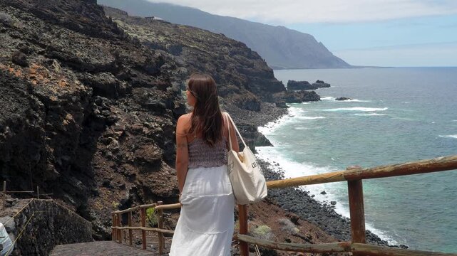 Beautiful woman turning and smiling by the volcanic coastline