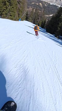 Snowboarder following a skier on a sunny day in the dolomites