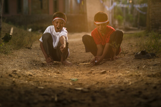 Indonesian boys playing traditional marbles game celebrating Independence Day on a village ground.