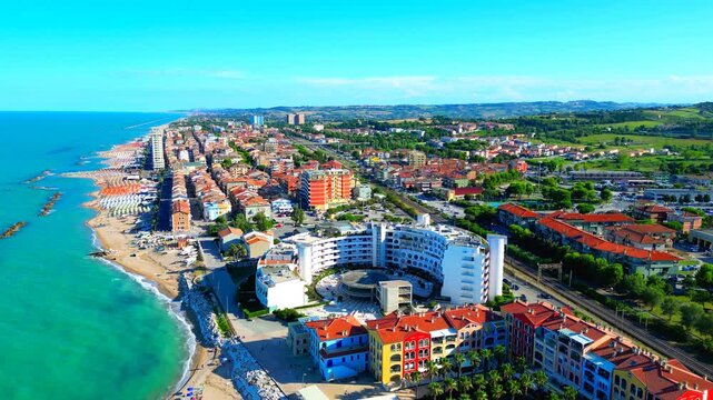 PORTO RECANATI, ITALY - JULY 30, 2025: Aerial push-in pedestal up tilt-down shot of the beach. The Paradiso Azzurro apartment complex is a calm seaside escape, located just 50 meters from the beach