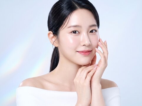 Beautiful young woman with clear skin touching her face