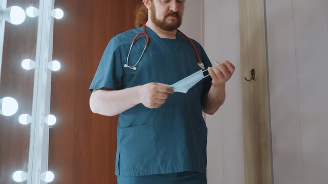 Medical professional adjusts mask orientation. Healthcare worker reviews fit and stance carefully. Medical practitioner assesses mask fit and body alignment before beginning rounds of visitation