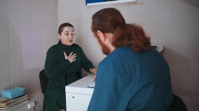Home paramedic assessing distressed patient clutching chest during urgent consultation at kitchen table, paperwork and medical kit visible, tense atmosphere, focused evaluation and breathing check,