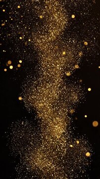 Sparkling golden particles and dust float against a deep black background, creating elegant bokeh