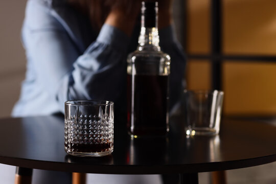 Alcohol addiction and substance abuse with a person in distress and a glass of whiskey on a table, Moody atmosphere, emphasizing the challenges of an unhealthy coping mechanism