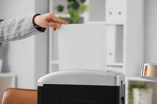 Person shredding confidential documents in an office paper shredder for data protection and privacy compliance