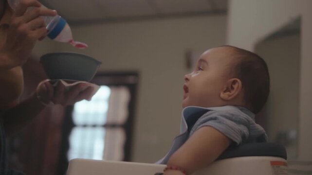 Mother feeding her smiling son with a spoon