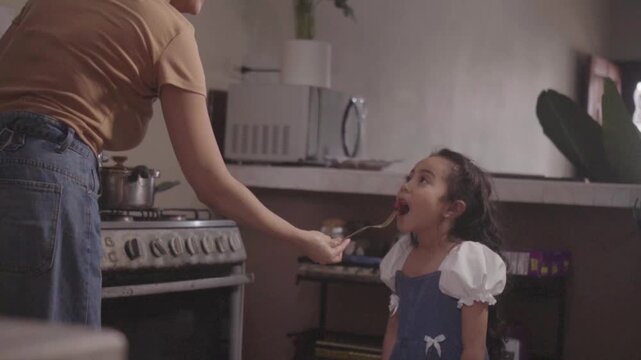 Mother feeding her little daughter in the kitchen