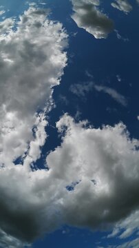 Vertical timelapse of a fisheye view of white summer clouds moving through a blue summer sky