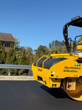 Sakai road roller beside newly paved asphalt roadway, guardrail and residential property - Pittsfield, Massachusetts, USA - September 29, 2025