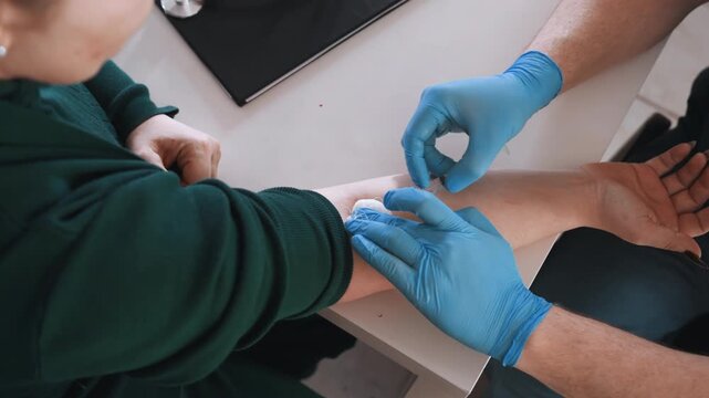 Closeup arm cleaning and dressing, emergency responder gently cleans forearm abrasion with antiseptic, gloved hands apply gauze and secure bandage on tabletop, steady technique and patient comfort