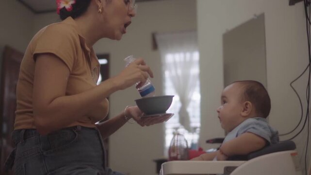 Joyful mother feeding her adorable son
