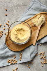 Fototapeta premium Glass bowl and wooden spoon with chickpea flour on grey background