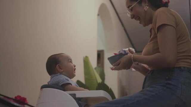 Mother feeding her infant son at home