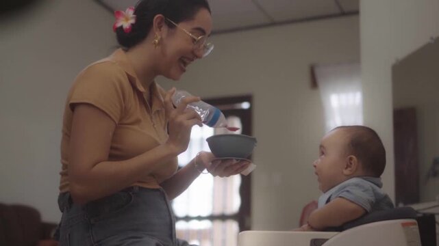 Mother feeding her infant son at home