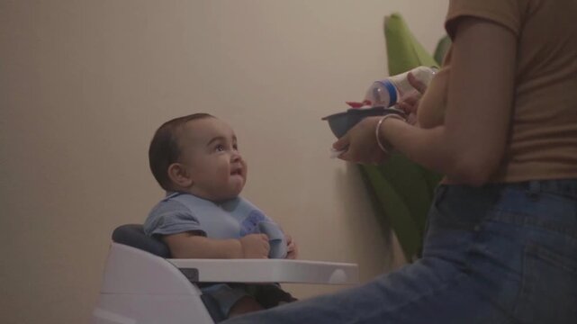 Mother feeding her toddler son at home