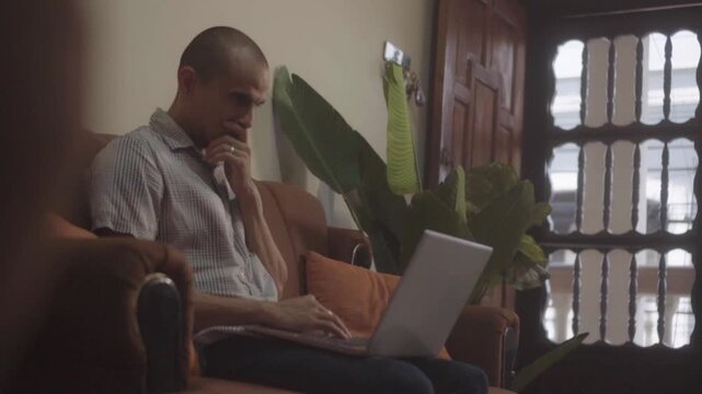Pensive male freelancer using laptop indoors