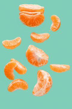 Flying pieces of sweet peeled mandarin on turquoise background