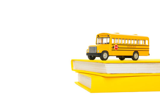 A school bus sits on top of two stacked books, isolated on white, PNG