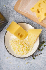 Fototapeta premium Plate and board with pieces of Swiss cheese on white table