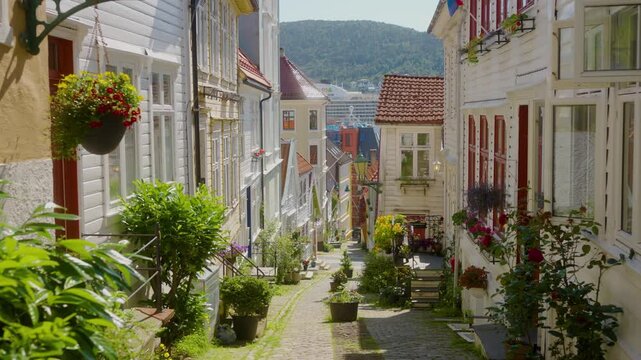 Smooth forward camera movement along Strangebakken, a picturesque historic street in Bergen, Norway. The narrow cobblestone lane is lined with traditional wooden houses, colorful doors and abundant 